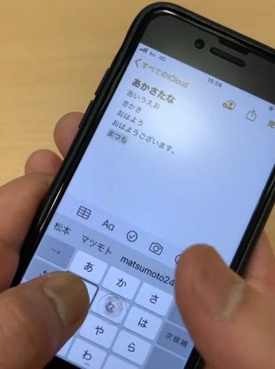 スマホを両手で持ち、左右の親指で画面を操作している。左手の親指で「た」キーを押さえたまま、スプリットタップを行なっている写真。